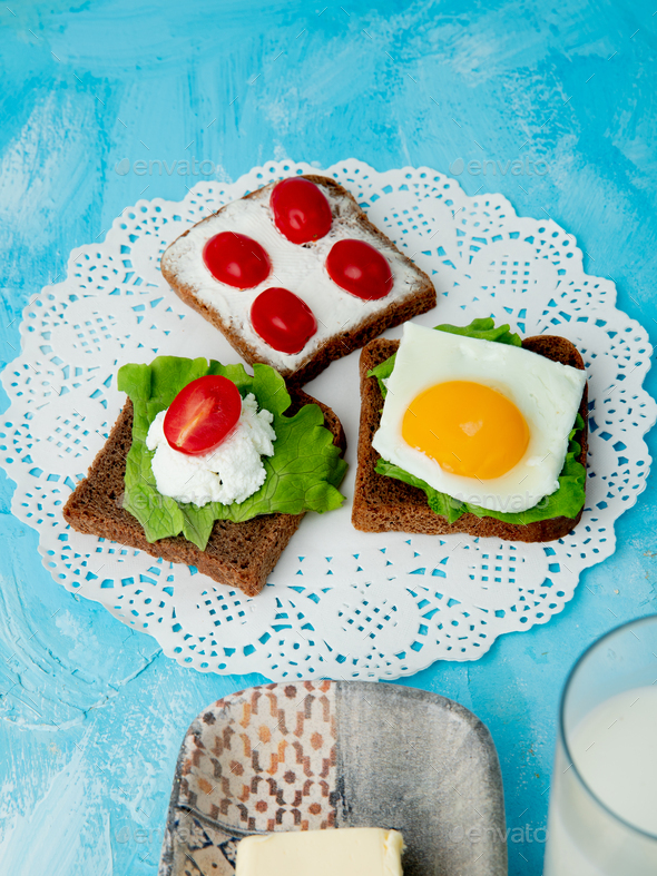 side view of sliced black breads with cottage cheese, spinach, tomato
